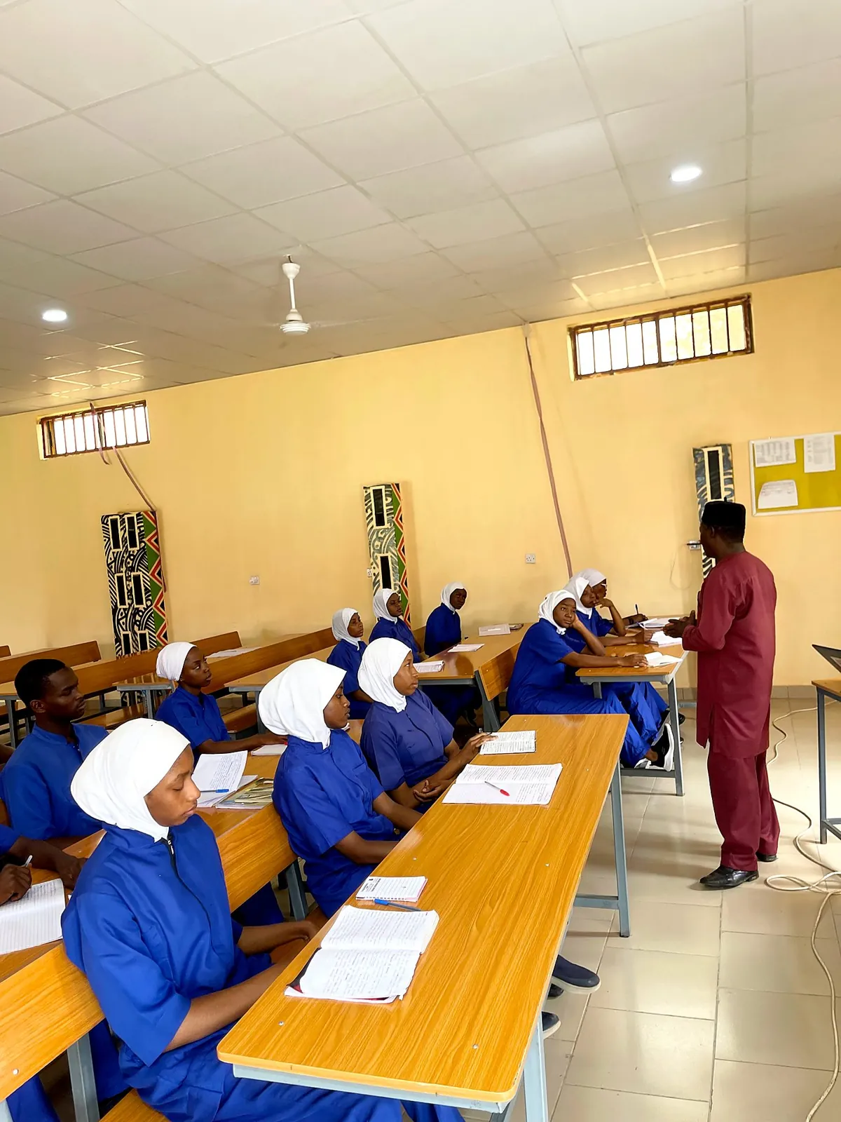 Student in blue scrubs listening in class